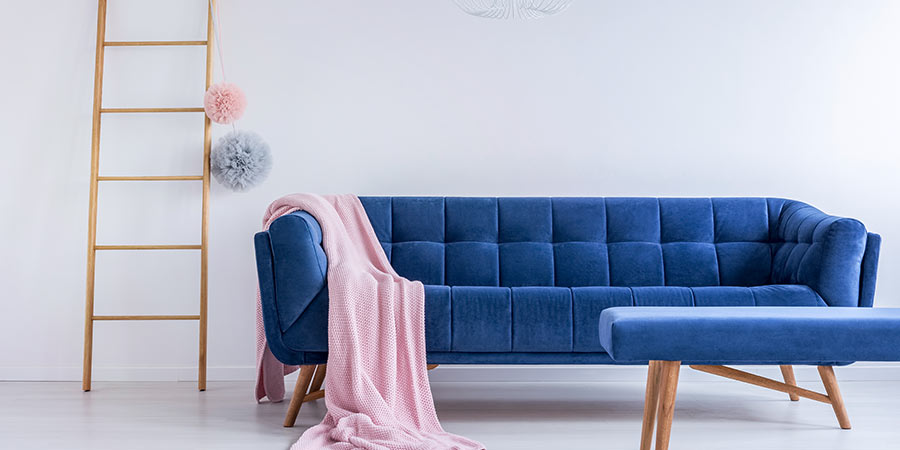 Blue Velvet Couch with Pink Blanket and Decorative Ladder in White Room 
