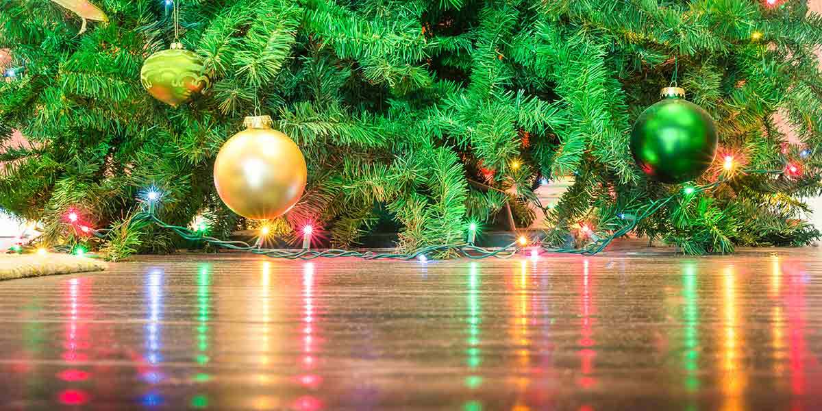 Christmas Tree with Ornaments and Lights on Hardwood Floor.